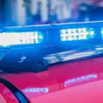 Nahaufnahme von blauen Notleuchten auf einem roten Feuerwehr- oder Einsatzfahrzeug mit unscharfem Hintergrund.